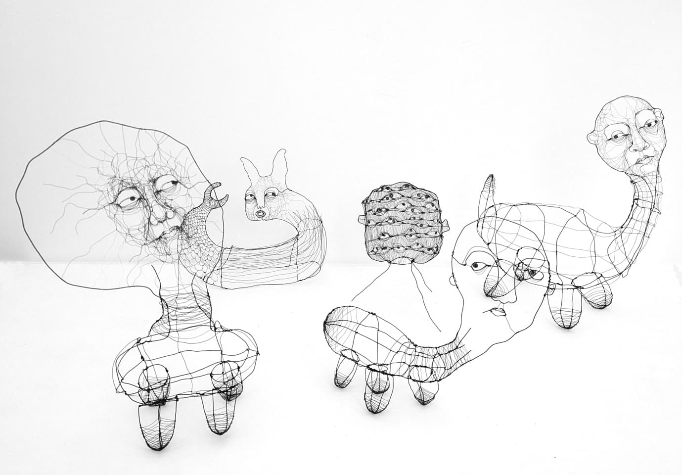 A group of Fiona Morley's wire creatures, part-human, part-animal, arranged together on a gallery floor