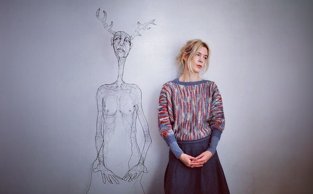 Fiona Morley beside one of her wire figures, a wire deer-antlered head rising above its shoulders
